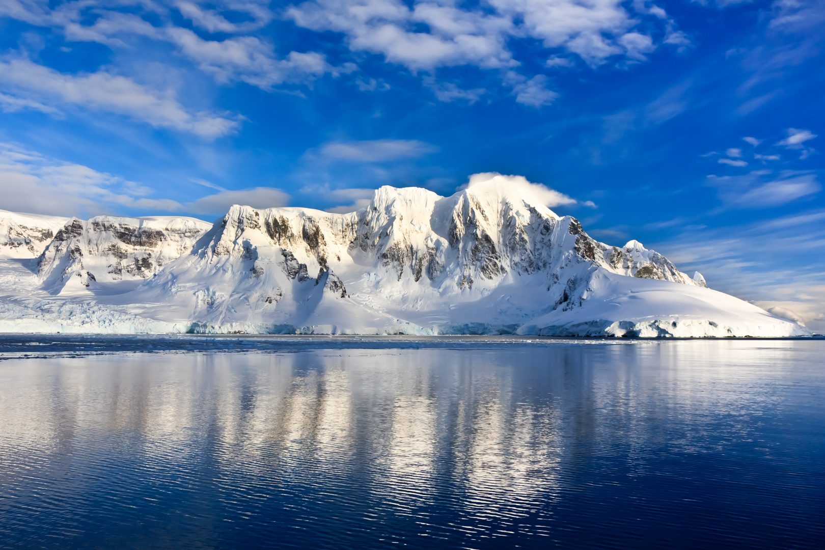 Mountains with snow and blue skies next to the sea