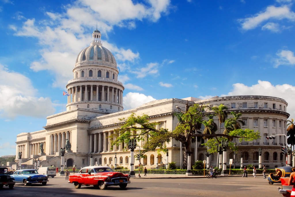 Classic american cars in front of hostoric building in Cuba