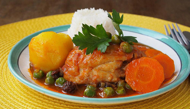 Close up of Estofado on a plate - meat stew served with carrot, potatoes, and rice