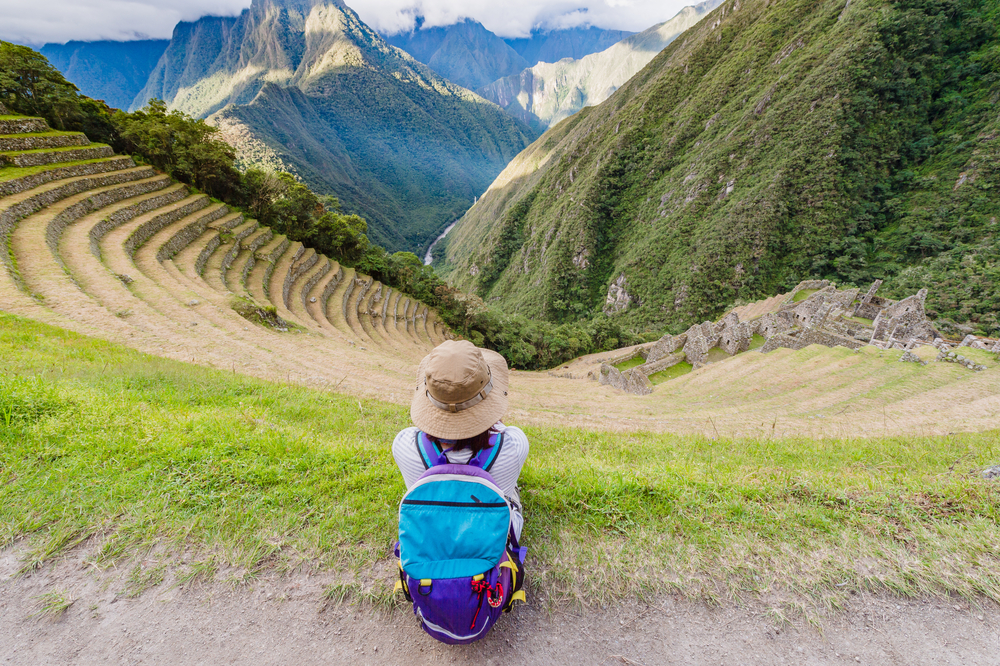 Woman sitting at the Terraced mountainside and buildings at Winay Wayna, The Inca Trail, Machu PIcchu, Cusco, Peru