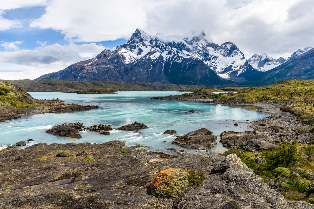 blue lake with snow capped mountains in the background 