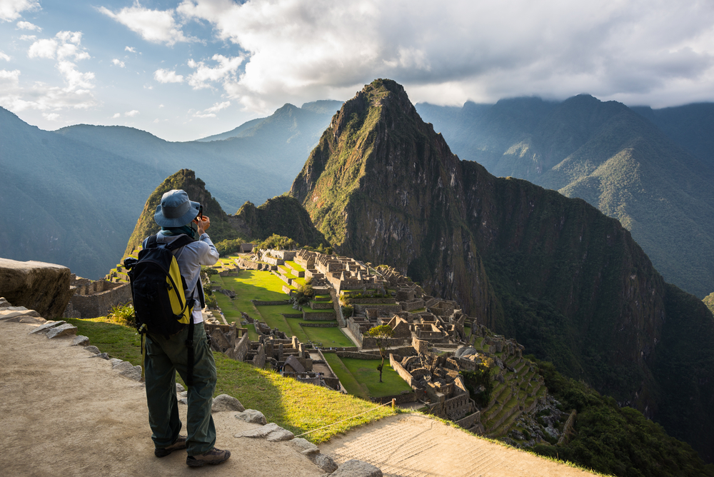 tourist in front of ancient ruin with mountain in background