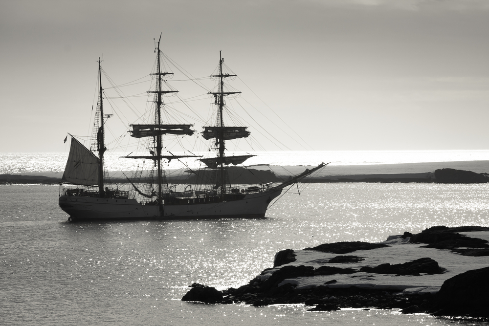 sailing ship in front of snowy coast