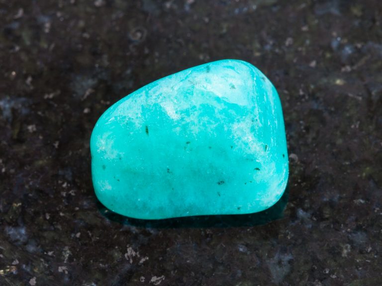 macro shooting of natural mineral rock specimen - tumbled amazonite gemstone on dark granite background from Braziln credit shutterstock