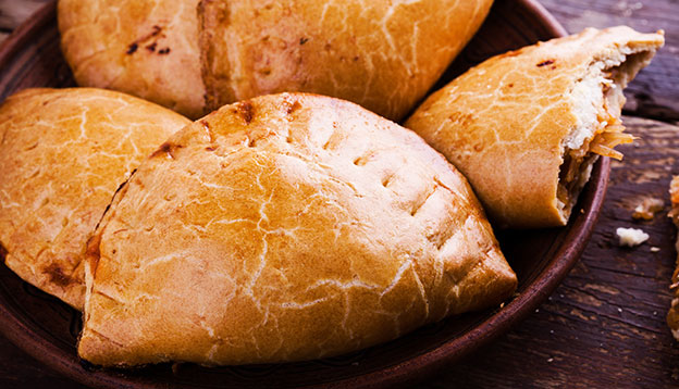 Homemade baked vegetarian empanadas, Latin-American-style stuffed vegetables pie with stewed cabbage, carrots, onions, tomatoes on rustic wooden background